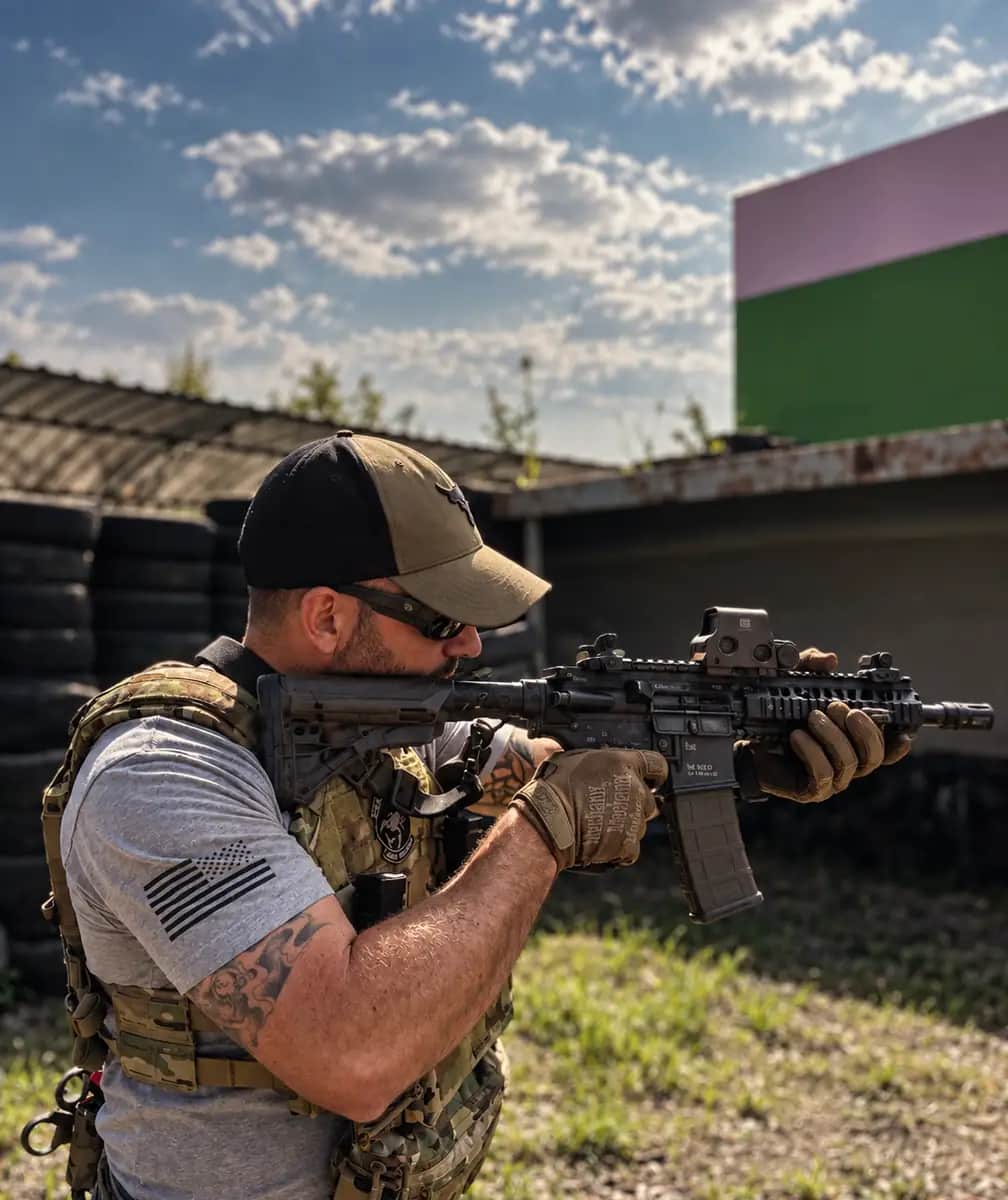 A shooter presenting a carbine from the high-ready on an outdoor range